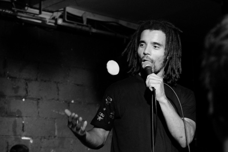 Black and white photograph of Akala performing on a darkened stage