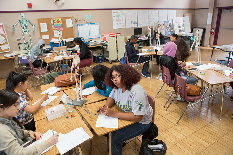 Diverse teenage school students sitting at desks in a classroom.