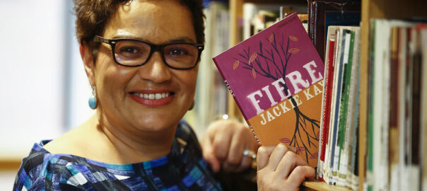 A photograph of Jackie Kay holding her collection Fiere